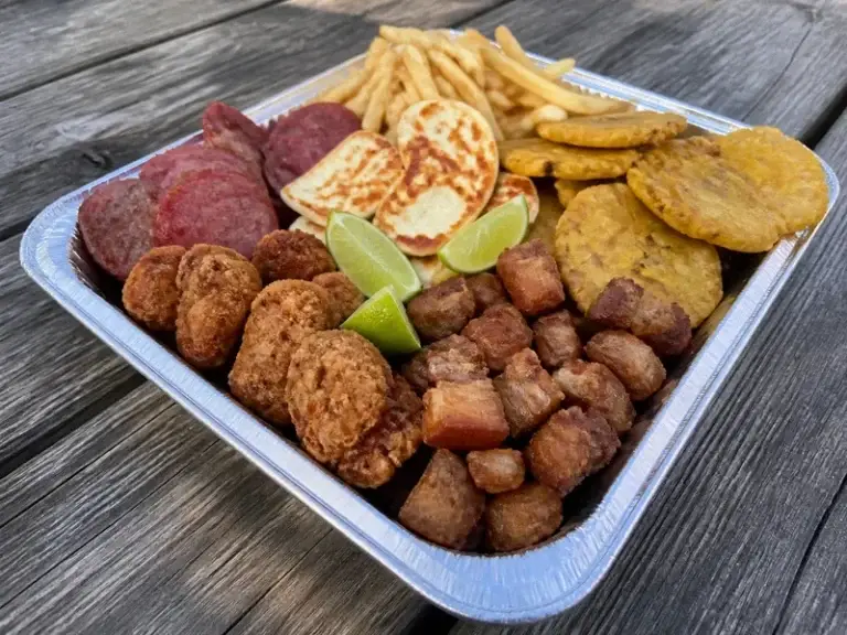 Dominican picadera platter with salami, fried cheese, tostones, fried pork and chicken bites, fries and lime